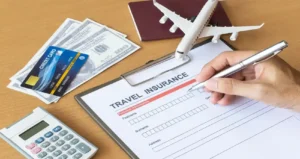 Student filling out travel insurance form with passport, credit card, dollars, and airplane model on desk